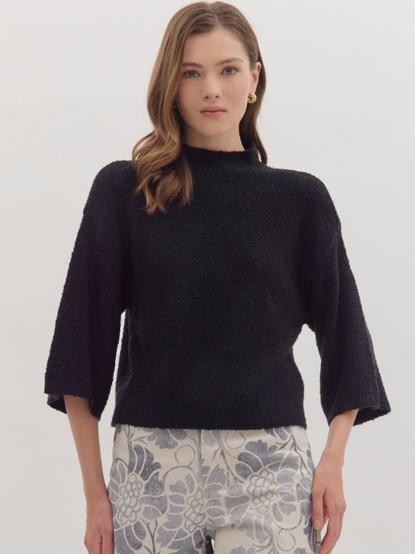 Woman wearing a black sweater with floral pants on a white background