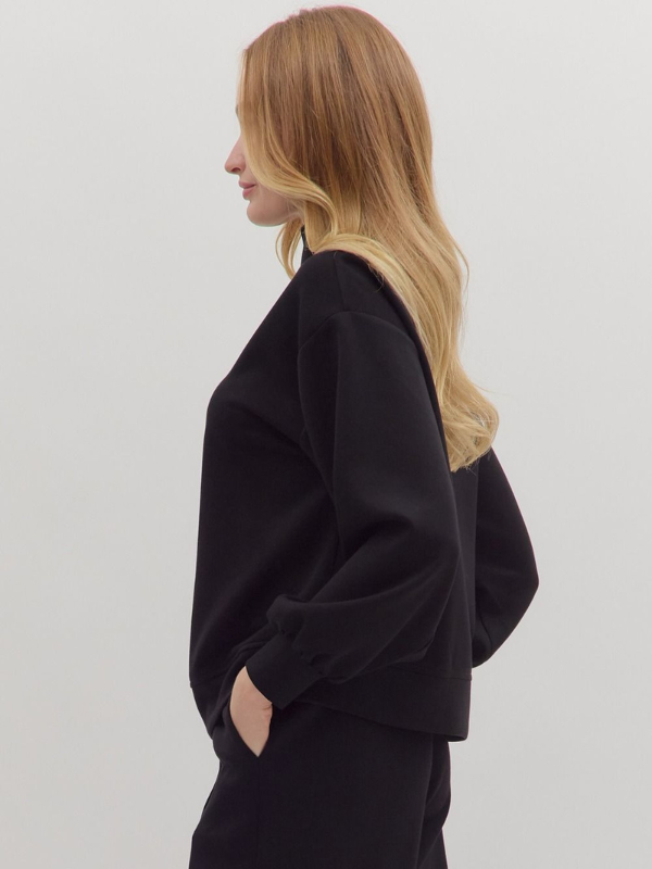 Person wearing a black outfit on a plain background