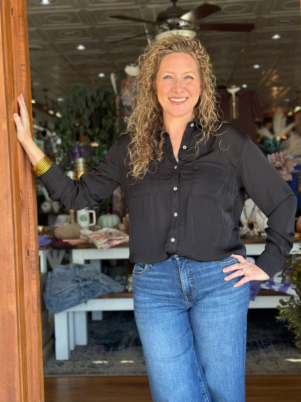 Woman standing in a store doorway wearing a black shirt and blue jeans.