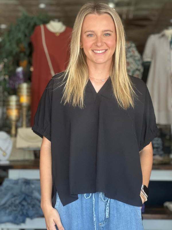 Woman wearing a black top and blue jeans in a clothing store.