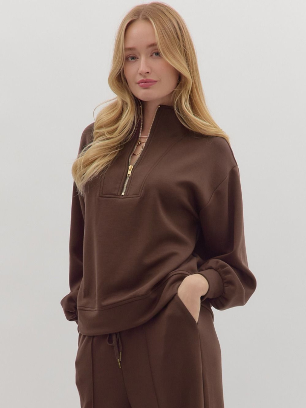 Woman wearing a brown outfit with a quarter-zip top on a white background