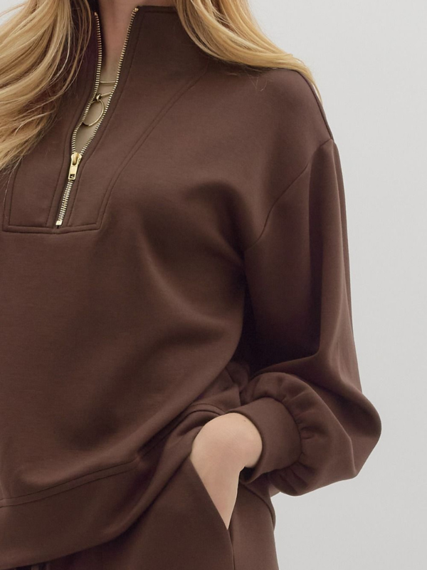 Brown half-zip sweatshirt worn by a person on a light gray background