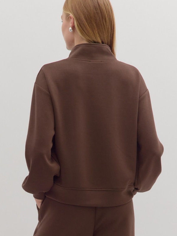 Person wearing a brown tracksuit against a white background