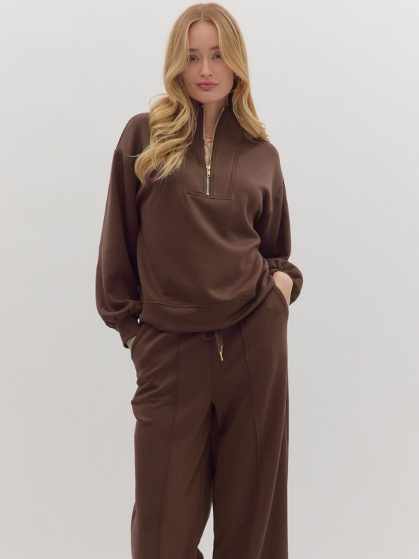 Woman wearing a brown tracksuit against a white background