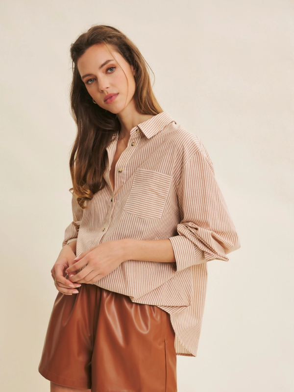 Woman wearing a beige checkered shirt and brown leather shorts on a plain background