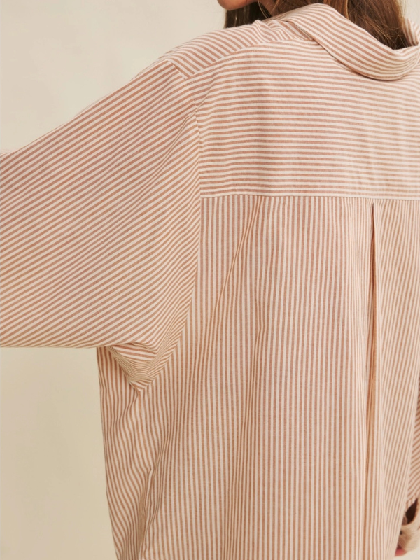 Close-up of a person wearing a beige striped shirt with a neutral background