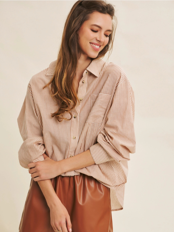 Woman wearing a striped shirt and brown pants against a beige background