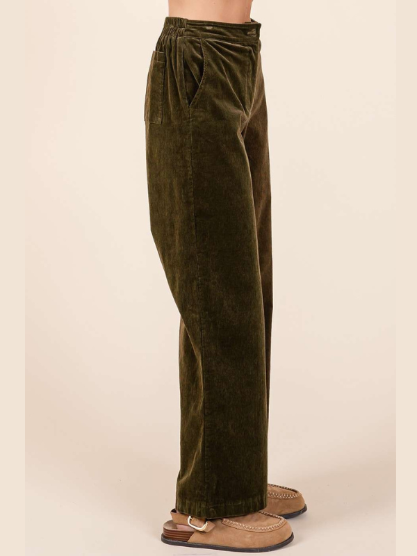 Brown velvet pants worn by a person on a beige background