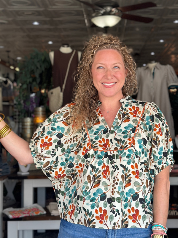 Woman wearing a colorful floral blouse in a store setting