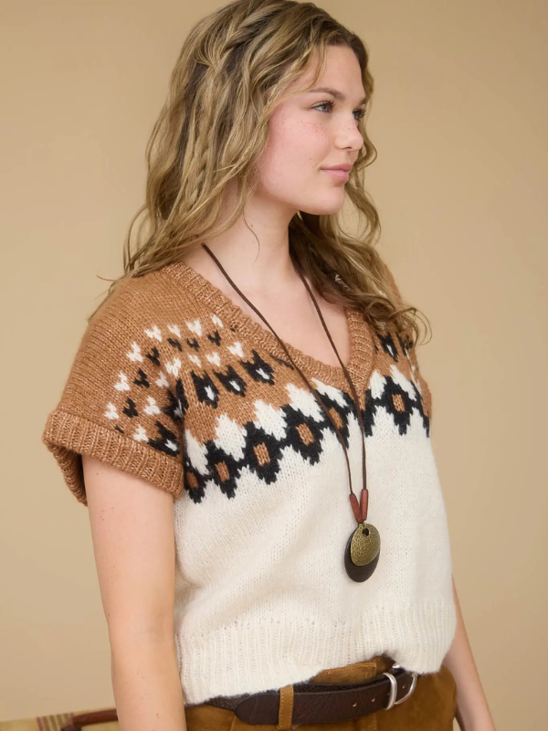 Woman wearing a patterned sweater vest against a beige background
