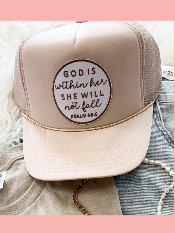 Beige trucker hat with 'God is within her, she will not fall' quote on a denim background