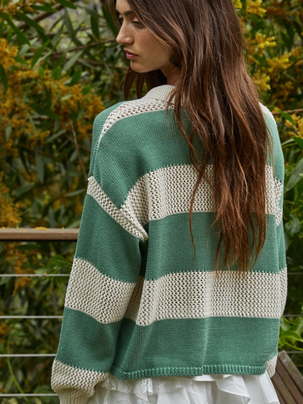 Woman wearing a green and white striped sweater with a blurred natural background