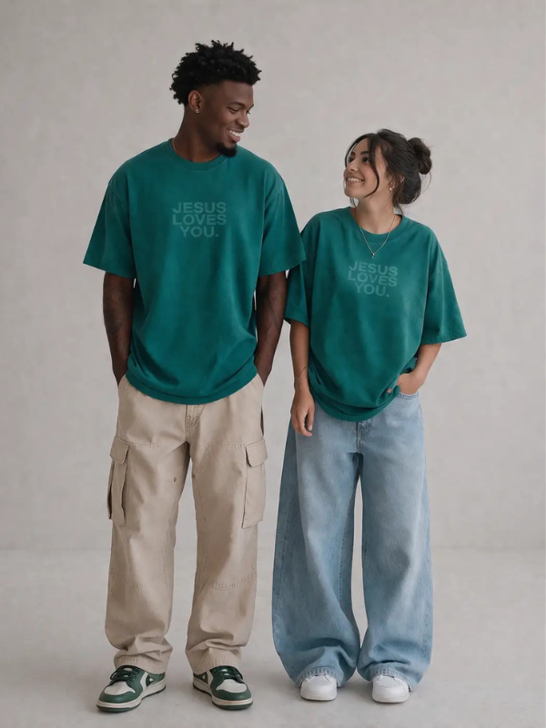 Two people wearing teal t-shirts with 'Jesus Loves You' text on a plain background