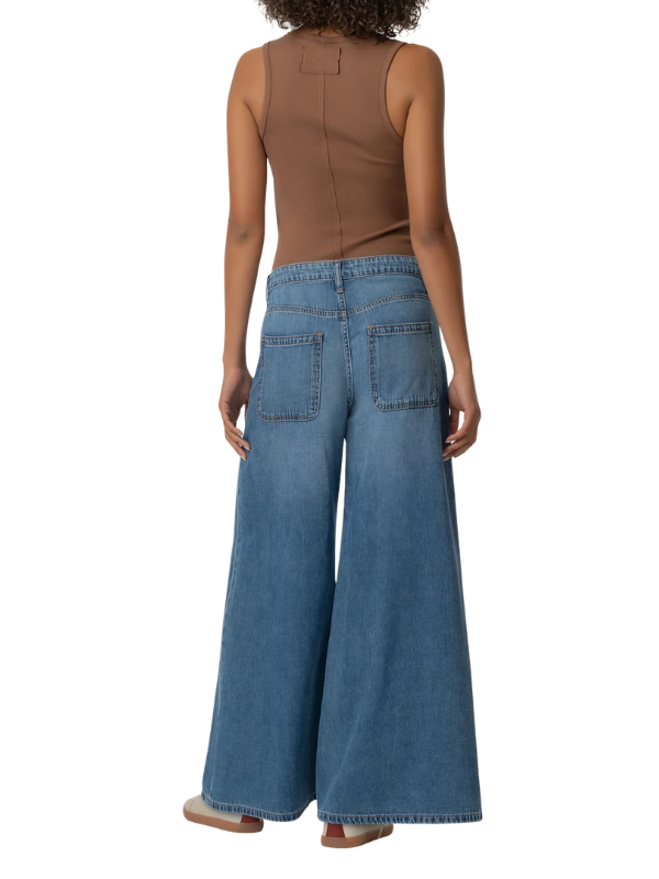 A model shown from the back wearing high-waisted, wide-leg blue denim jeans and a brown sleeveless top against a plain white background.