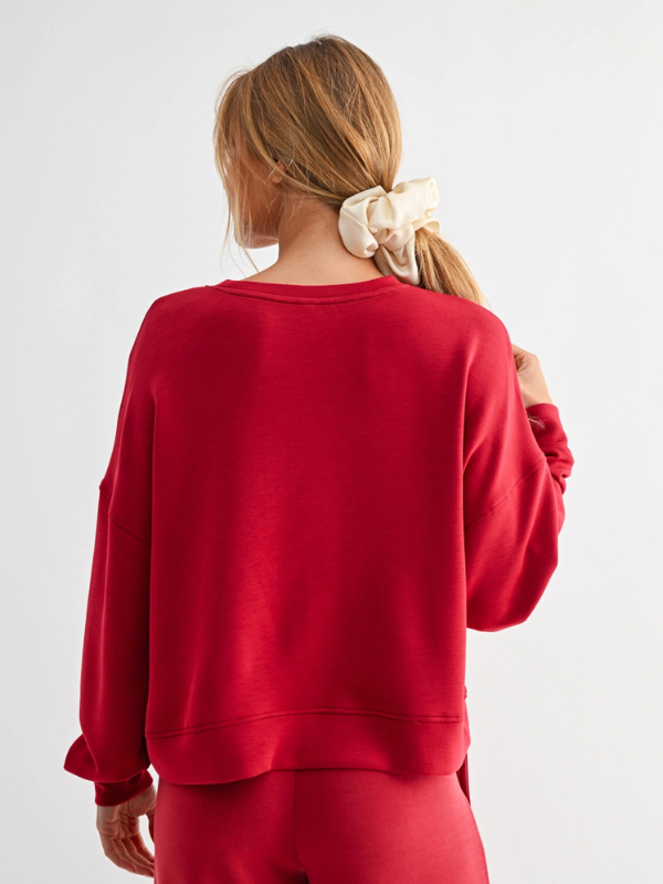 Person wearing a red sweatshirt on a plain background