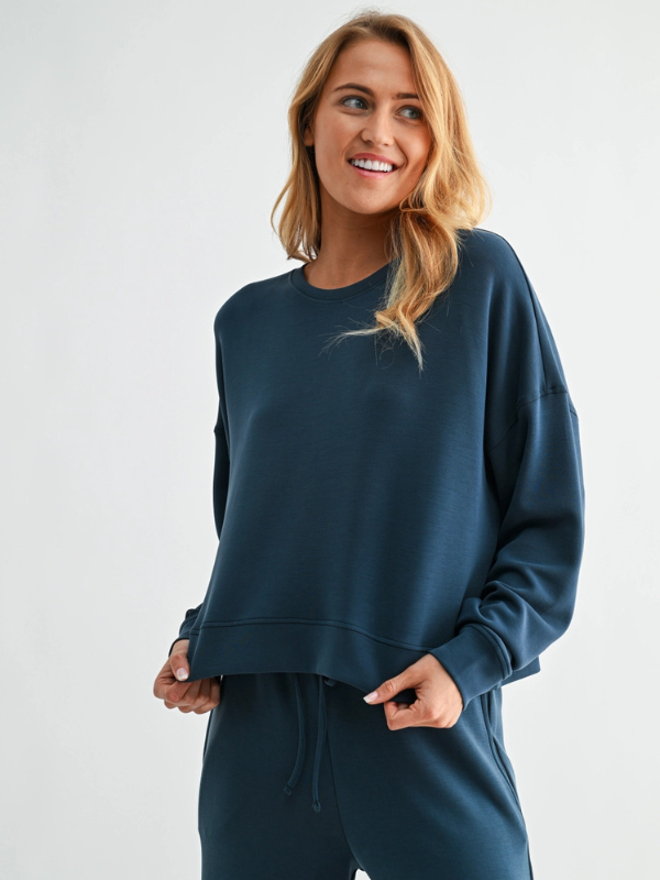 Woman wearing a teal sweatshirt and pants on a white background