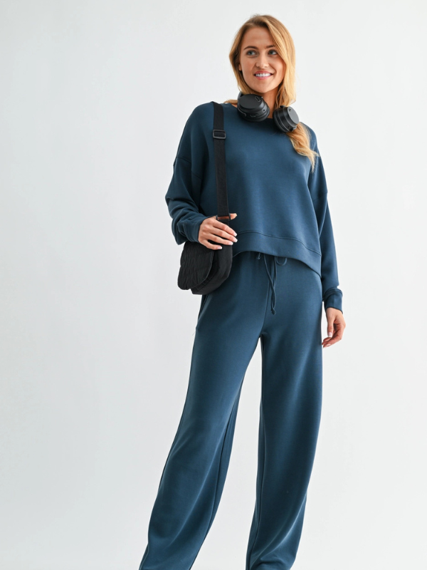 Woman wearing a blue outfit with a black bag on a white background
