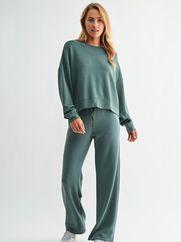 Woman wearing a green sweatshirt and pants on a white background