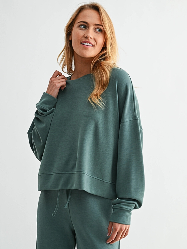 Woman wearing a green sweatshirt and pants on a white background