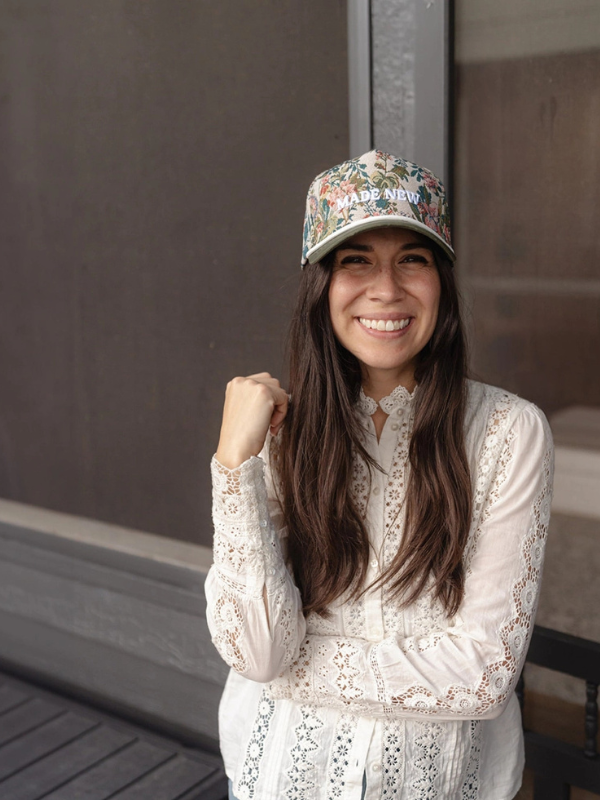 Woman wearing a floral cap and white lace top outdoors