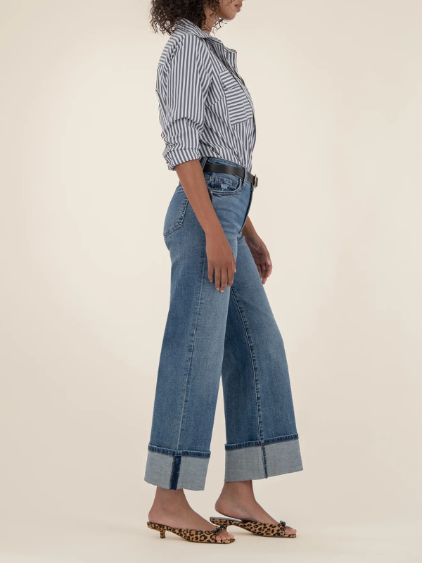 Person wearing a striped shirt and wide-leg jeans on a beige background
