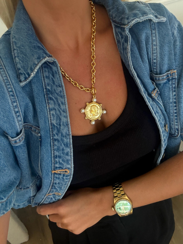 Person wearing a gold necklace and watch with a denim jacket