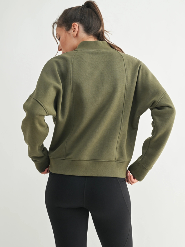 Person wearing a green jacket and black pants on a white background
