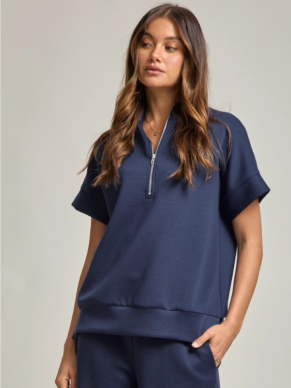 Woman wearing a navy blue zip-up top against a neutral background
