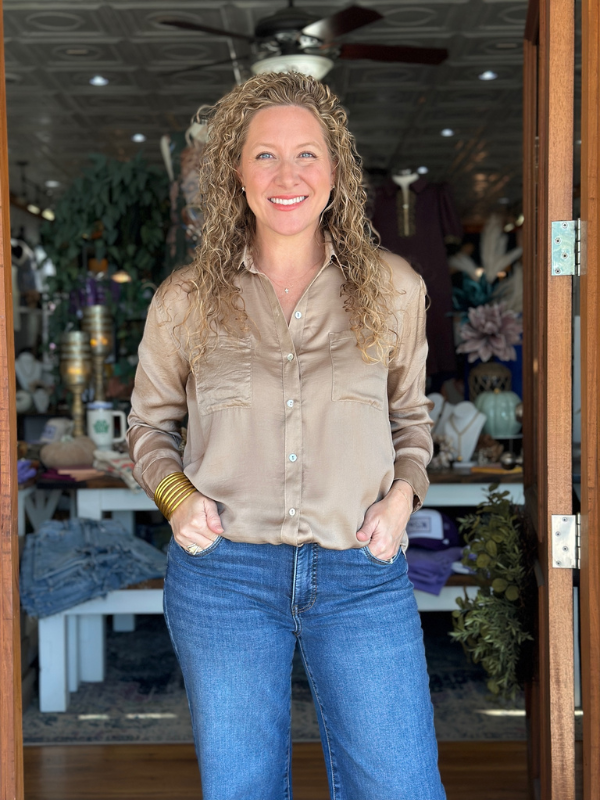 Woman wearing a beige shirt and blue jeans standing in a store.