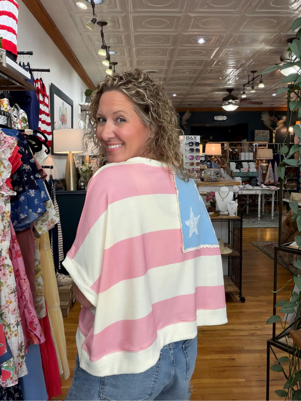 Woman wearing a pink and white striped poncho with a star design in a store.