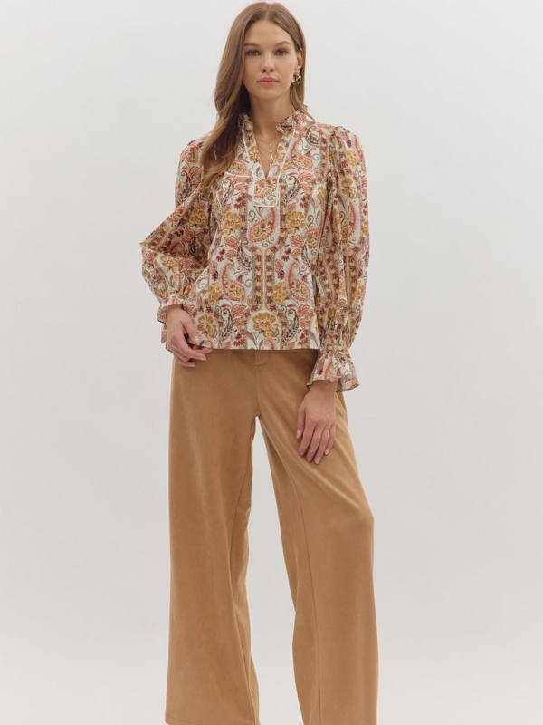 Woman wearing a patterned blouse and beige pants on a white background