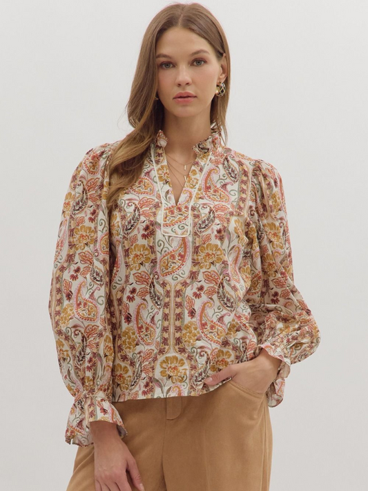Woman wearing a patterned blouse with long sleeves on a plain background