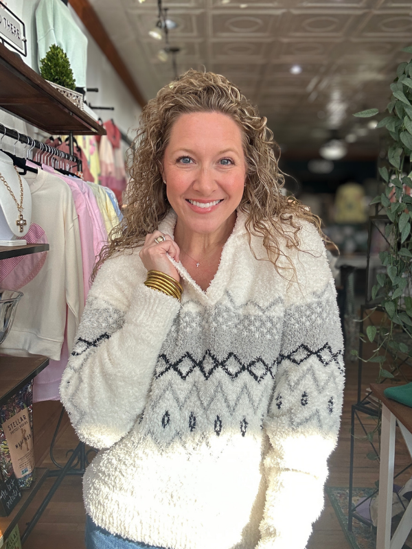 Woman wearing a patterned sweater in a store setting
