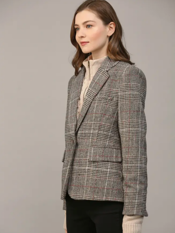 Woman wearing a plaid blazer against a plain background