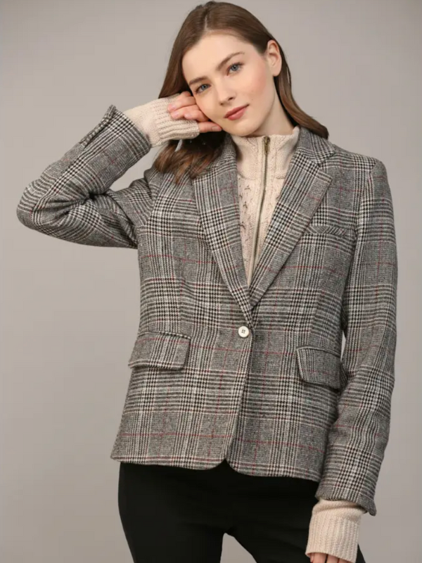 Woman wearing a gray checkered blazer over a beige sweater on a plain background