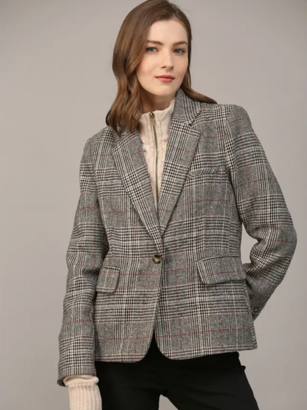 Woman wearing a gray checkered blazer against a plain background