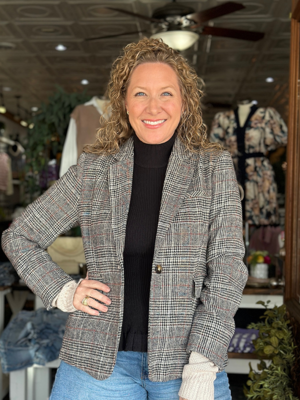 Woman wearing a gray checkered blazer in a store setting