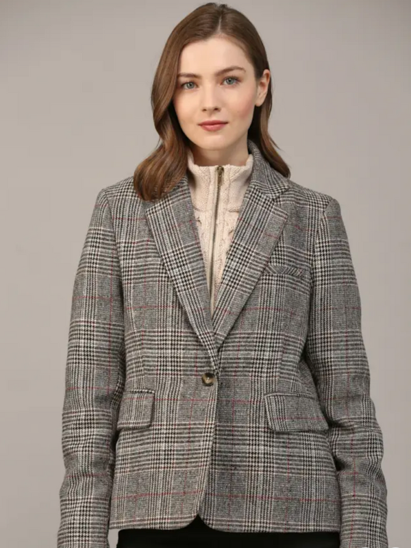 Woman wearing a gray checkered blazer against a plain background