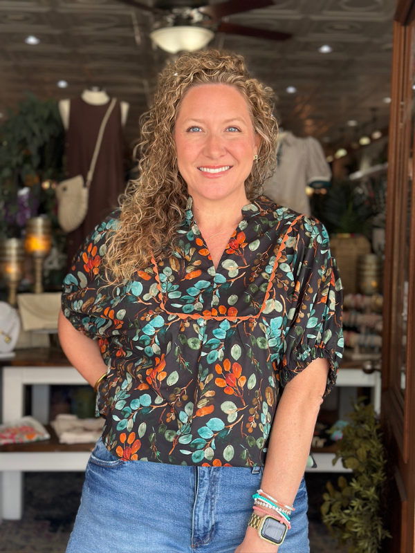 Woman wearing a patterned blouse and jeans in a store setting