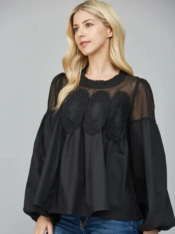 Woman wearing a black blouse with sheer lace details on a gray background