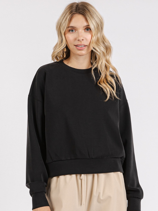 Woman wearing a black sweater and beige pants on a white background