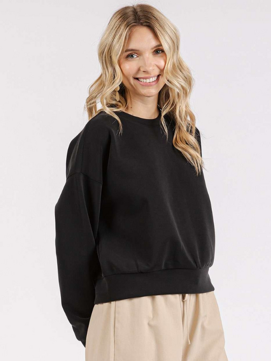 Woman wearing a black sweater and beige pants on a white background