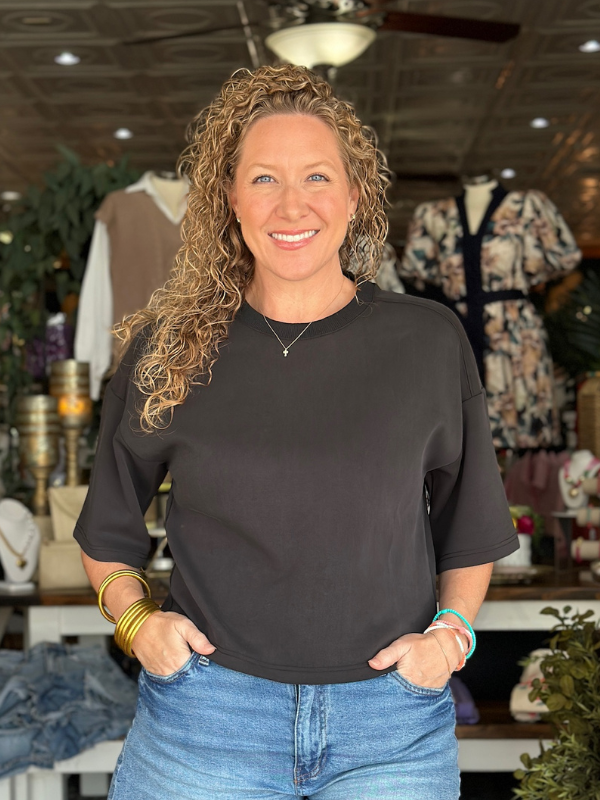Woman wearing a black top and blue jeans in a store setting