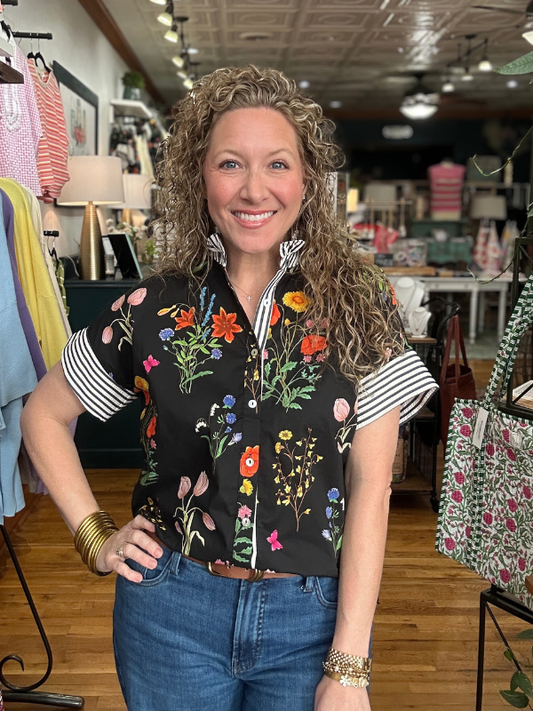 Woman wearing a floral blouse and jeans in a store setting