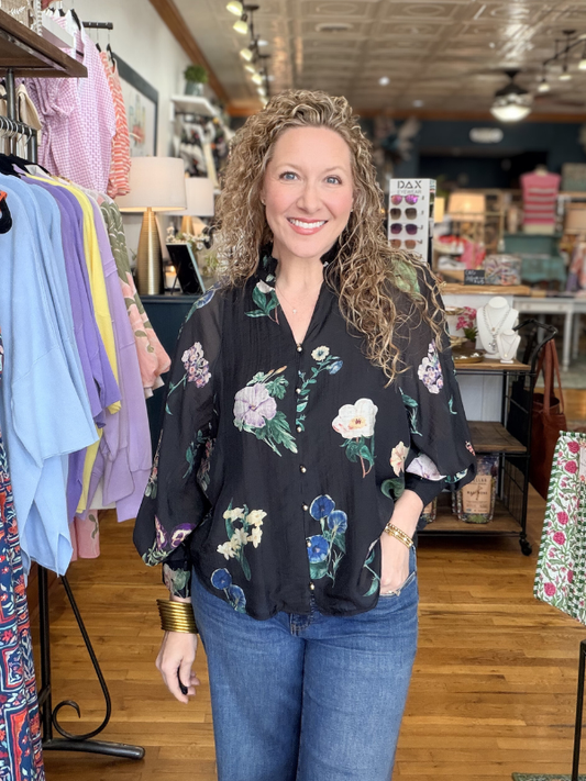 Woman wearing a floral blouse and jeans in a store setting
