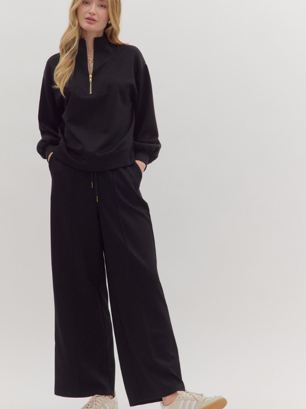 Person wearing a black outfit with a high collar on a white background