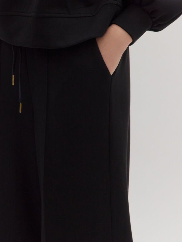 Black pants with a drawstring on a light gray background