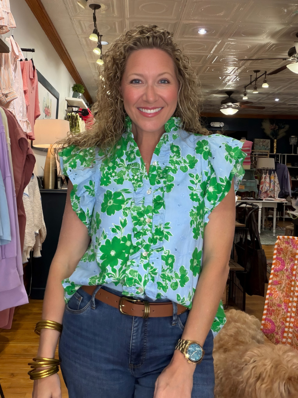 Woman wearing a green floral blouse in a clothing store