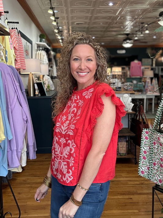 Woman wearing a red floral top in a store setting