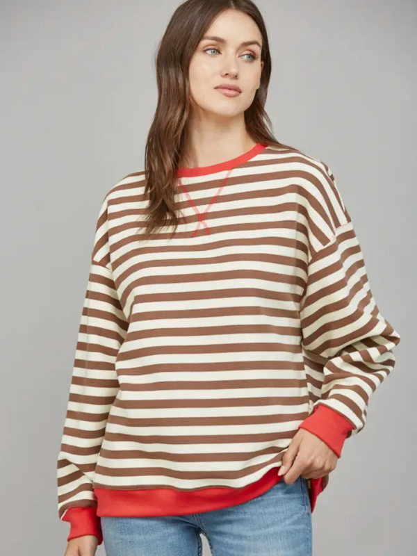 Woman wearing a brown and beige striped sweater with red trim on a gray background
